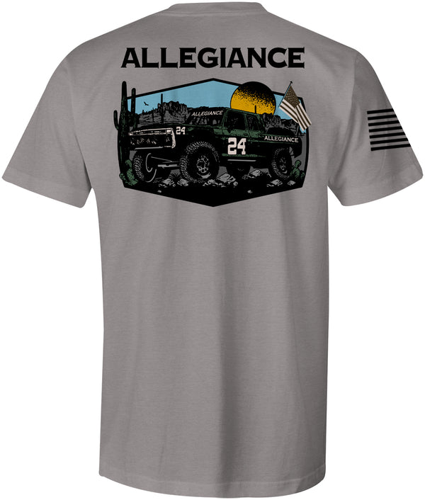 Back of Baja Premium Tee in gray showcasing large graphic of an off-road racing truck in a desert setting with mountains, sunset, and American flag.